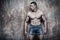 Handsome muscular man, abs, on wall background