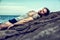 Handsome muscular man on the beach sitting on rocks