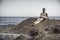 Handsome muscular man on the beach sitting on rocks