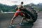 Handsome muscular man flipping big tire outdoor.