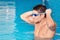 Handsome muscular man standing inside the pool putting on his swimming googles.