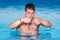 Handsome muscular man standing inside the pool putting on his swimming googles.