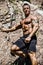 Handsome, muscular, shirless climber climbing rock