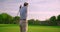 Handsome older golfer swinging and hitting golf ball on beautiful course at sunset.