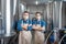 Handsome owners of brewery in masks and aprons, near brewing kettles