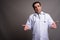 Handsome Persian man doctor against gray background