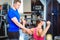 Handsome personal trainer guiding a beautiful woman at a modern fitness club