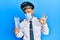 Handsome pilot man with beard wearing safety mask holding boarding pass doing ok sign with fingers, smiling friendly gesturing