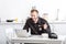 Handsome police officer eating cornflakes and using laptop