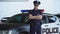 Handsome police officer smiling, standing near new patrol car, law and order