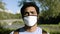 A handsome portrait of a black man wearing a medical mask in a beautiful park.