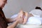 Handsome practicing masseur kneads feet of female client, who li