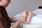 Handsome practicing masseur kneads feet of female client, who li