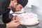 Handsome professional confectioner making a delicious cake in the pastry shop.