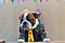 A handsome redneck English Bulldog wearing a straw hat and green striped shirt on the tent bench