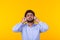 Handsome relaxed indian man with beard is listening to favorite music at the earphones on yellow background. Music