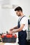 Handsome repairman opening toolbox while standing