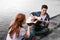 Handsome romantic boyfriend playing the guitar for his girlfriend sitting near river