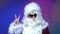 Handsome santa claus at night club doing victory sign with fingers to the camera