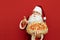 Handsome Santa Claus pizza deliveryman isolated on red background with pizza box in his hands shows his hand in hot tasty pieces