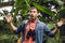 Handsome scared and shocked traveler with binoculars and backpack in green tropical forest.