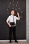 Handsome school boy in googles white shirt tie standing close to school desk with numbers above around the head.