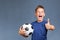 Handsome screaming caucasian fan boy holds soccer ball and gesturing thumbs up