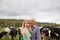 Handsome Senior Farmer and His Young Blonde Wife Hugging in Front of Their Black and White Cows Outdoors.