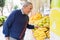 Handsome senior man at fruit store stand smiling buying fresh organic groceries