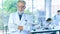 Handsome senior scientist man wearing white dress coat stand in front interior laboratory background smiling positive. Successful