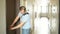 Handsome serious man in grey t-shirt closing the door of his apartment with keys and leaving
