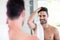 Handsome shirtless man looking in the mirror