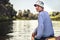 Handsome simple teenager boy traveling by boat on river during countryside summer camp holidays