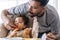 Handsome single young father feeding spaghetti for his mixed race daughter while baby girl sitting on high chair. Infant cute