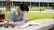 A handsome and smart Asian college man is focusing on reading a book in the campus park