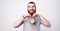 Handsome smiling bearded man is holding a cute little clock near his face looking at the camera