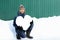 Handsome smiling bearded man in winter clothes holding a big heart made of snow, on green wall background. Declarations of love,