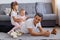 Handsome smiling brunette father playing with his daughters while lying on floor near sofa, wearing white t shirt, children