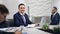 Handsome smiling businessman posing at workplace in modern white office interior