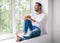 Handsome smiling man relaxing on window sill