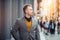 Handsome smiling young adult businessman standing outdoors  near wall on city street.