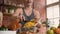 Handsome smiling young man is cutting yellow paprika and trying puts chopped pieces in glass bowl for preparing fresh