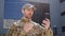 Handsome soldier in a cap having online video call with his family outdoors.