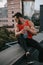 handsome sportsman sitting on roof railing with bottle of water