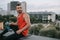 handsome sportsman sitting on roof railing with bottle of water