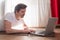 Handsome strong sportsman on floor in living room using laptop computer