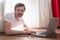 Handsome strong sportsman on floor in living room using laptop computer