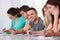 Handsome student sitting with classmates writing at desk