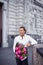 A handsome stylish man in a white shirt and black trousers and a bouquet of peonies in his hands