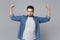 Handsome stylish unshaven young man in denim jeans shirt posing isolated on grey wall background studio portrait. People